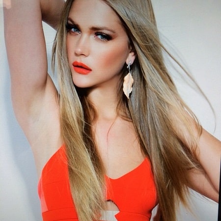 A picture of Esti Ginzburg wearing orange dress.